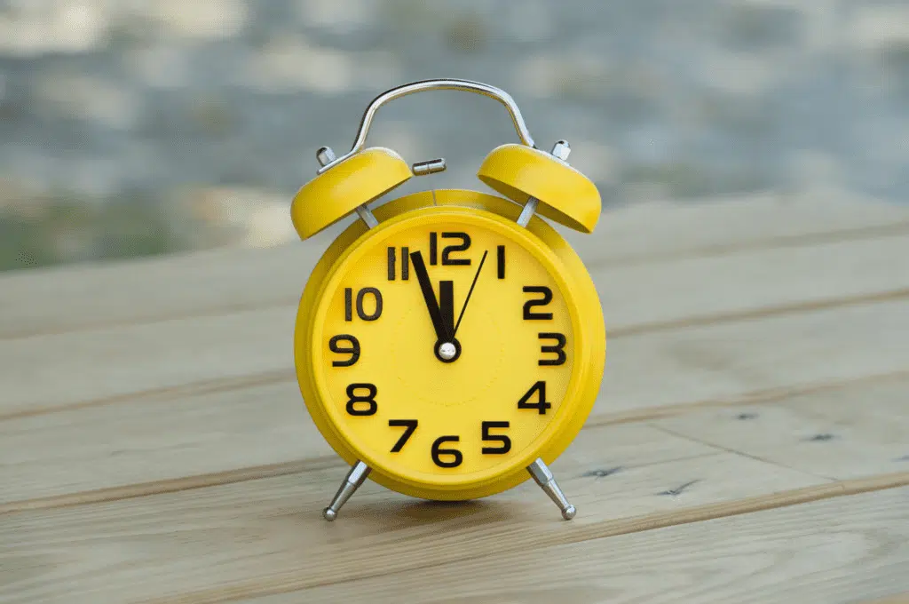 A bright yellow clock sitting on a wooden porch, symbolizing Right Time HVAC’s commitment to timely heating and cooling services.