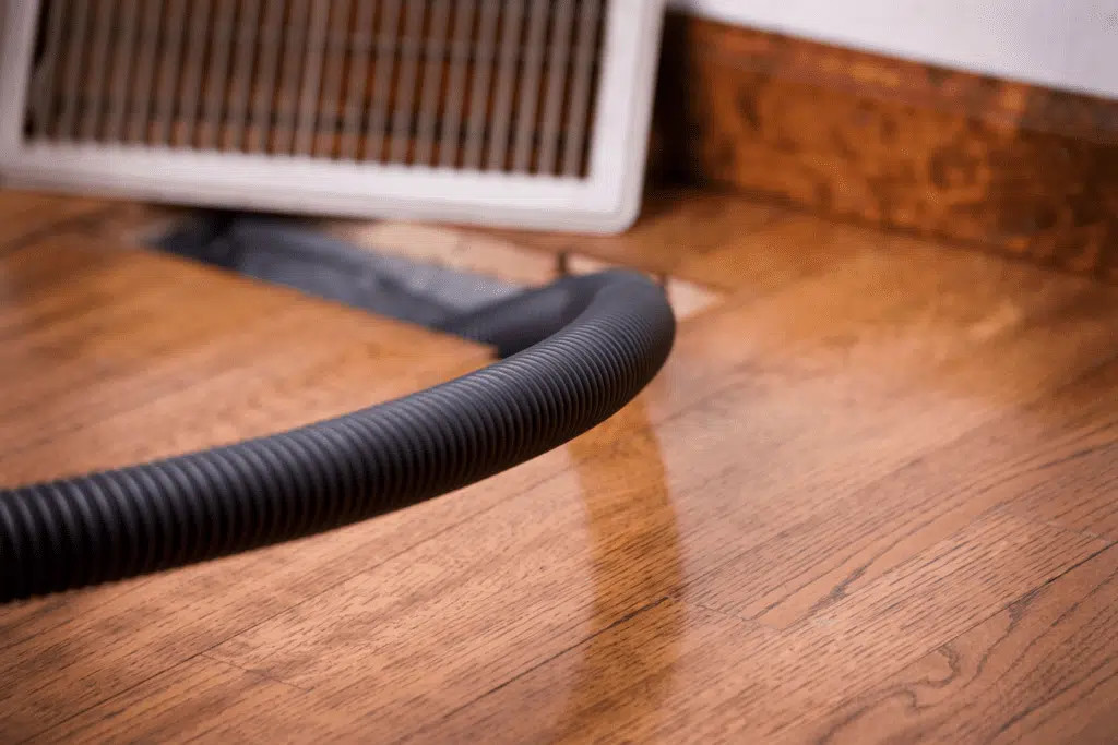 An open vent with a tube running into it, showing an HVAC system’s air distribution in a home.