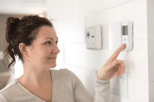 happy woman looking at the thermostat at her home