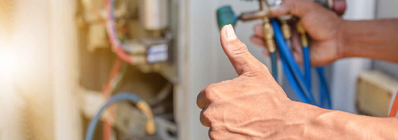 An HVAC technician using gauges to check the refrigerant levels of an air conditioning system.