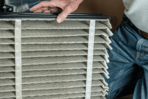 A person changing out an air filter for an AC unit to improve airflow and indoor air quality. AC repair in belle meade