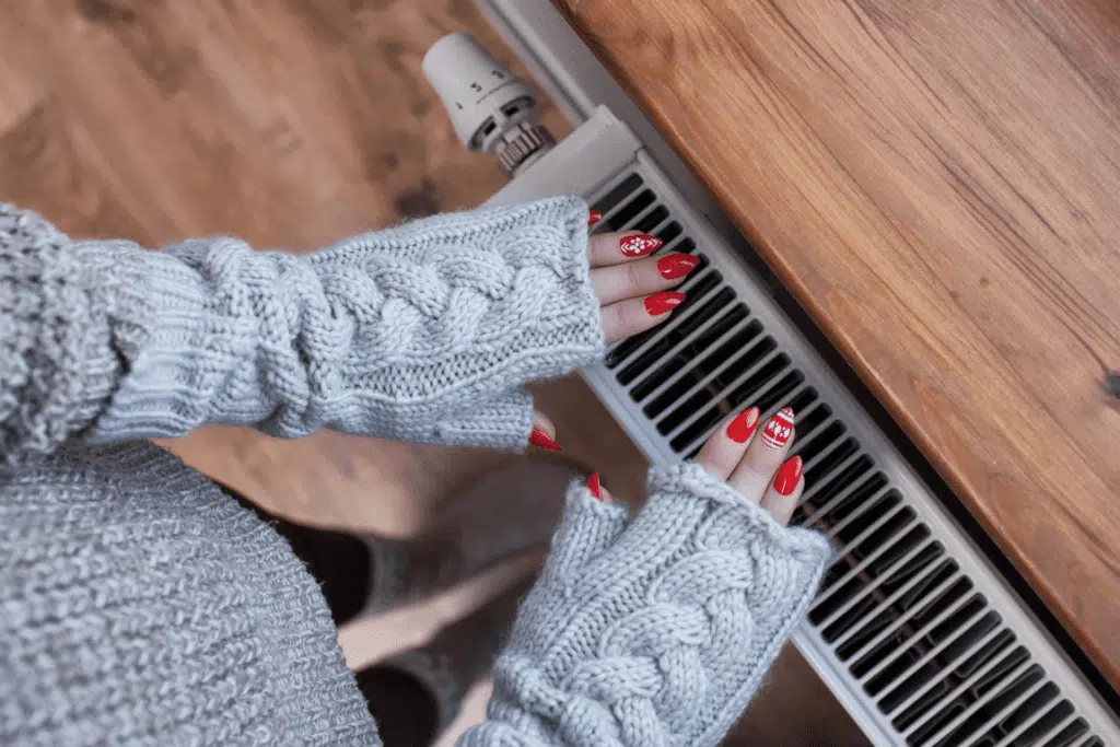 woman with hands over a heater