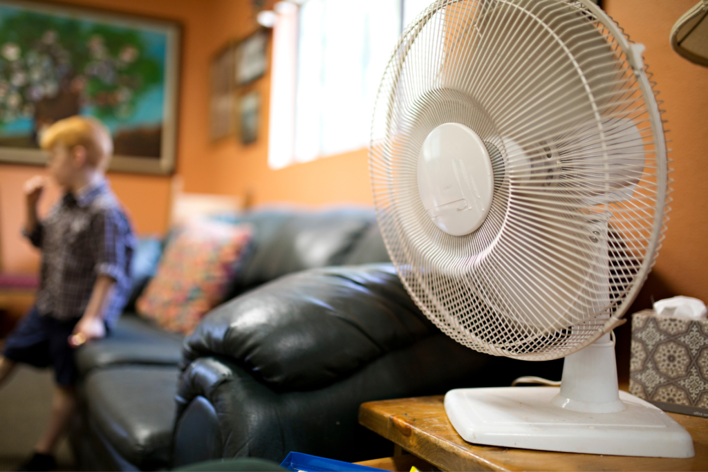 boy hanging out in living room with floor fan